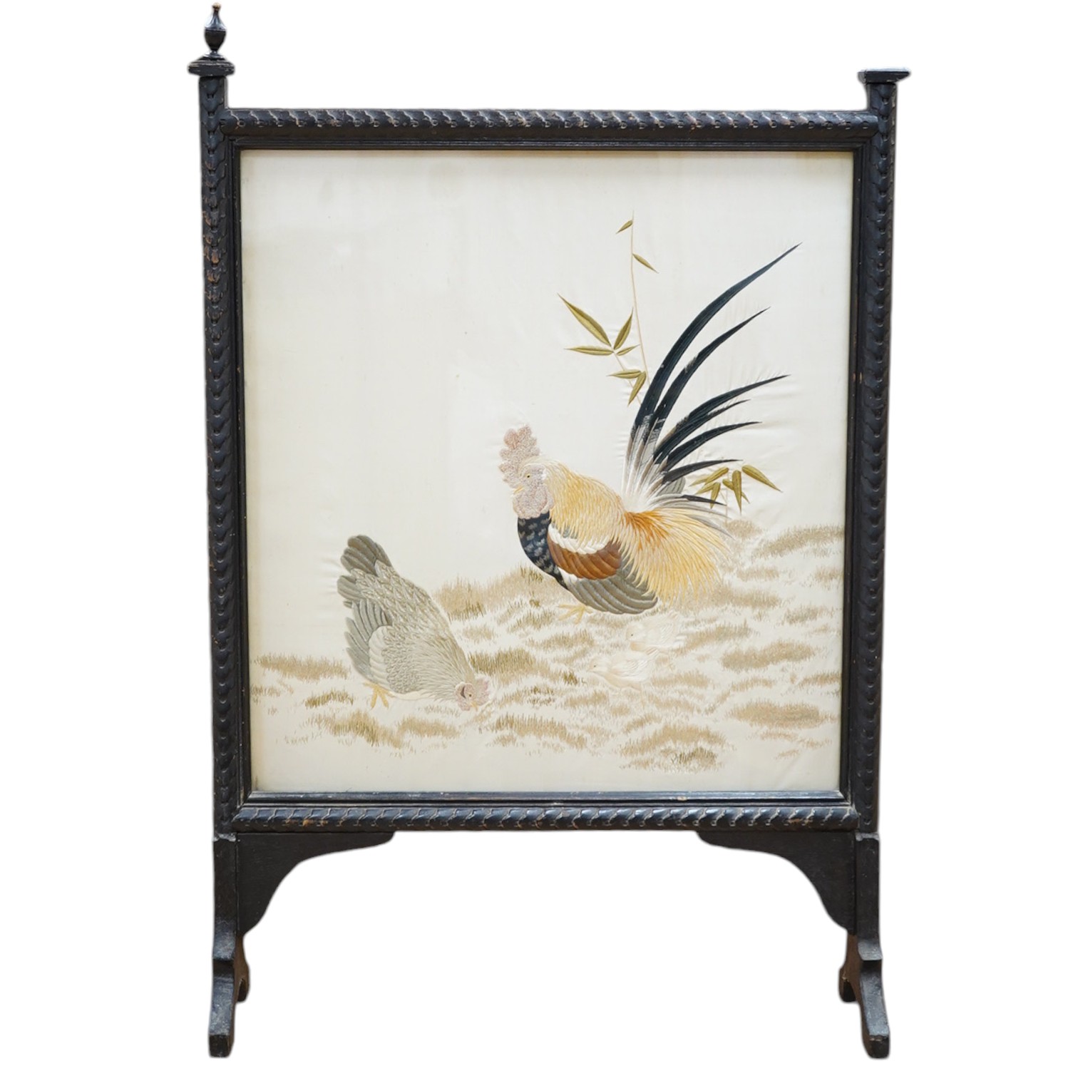 A Victorian fire screen inset with a Japanese cream silk embroidered panel of a cockerel, hen and two chicks, beautifully embroidered with rows of couched silk on the bodies of all the birds, their feathers and faces inc